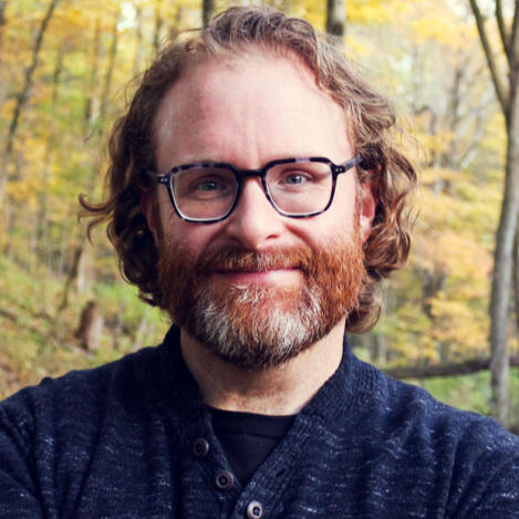 Josh Smith, professional voice actor, wearing a dark black sweater suit with a friendly expression.